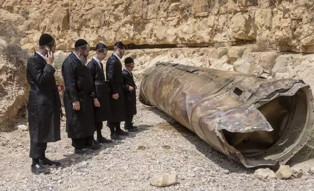 Ultra-Orthodox Jews observe the part of the intercepted ballistic missile that fell in the desert near the city of Arad, Israel, Sunday, April 28, 2024. The suspected Israeli killing of Iranian generals at an Iranian diplomatic compound in Syria on April 1 prompted Iran's retaliatory barrage last weekend of more than 300 missiles and drones that the U.S., Israel and regional and international partners helped bat down without significant damage in Israel. And then came Friday's apparent Israeli strike. (AP Photo/ Ohad Zwigenberg)