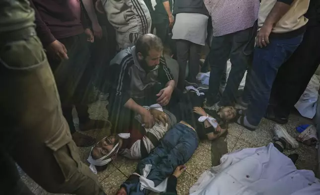 Palestinians mourn next to dead ones in the Al Aqsa hospital in Deir al Balah following an Israeli bombardment in the Maghazi refugee camp, central Gaza Strip, Tuesday, April 16, 2024. Several killed in a strike in Maghazi camp in Central Gaza on Tuesday. (AP Photo/Abdel Kareem Hana)