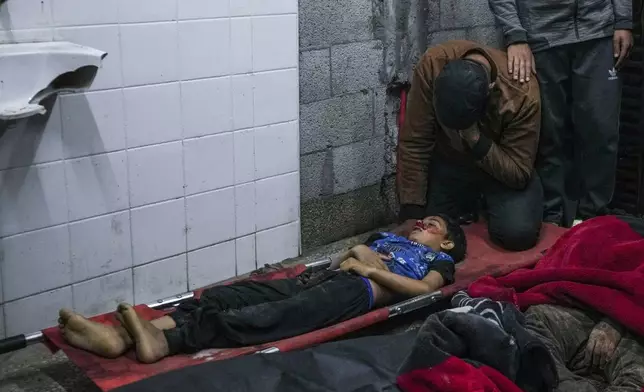 A man reacts next to the body of a boy killed in an Israeli bombardment of the Gaza Strip at al Aqsa Hospital in Deir al Balah, Gaza Strip, Tuesday, April 9, 2024. (AP Photo/Abdel Kareem Hana)