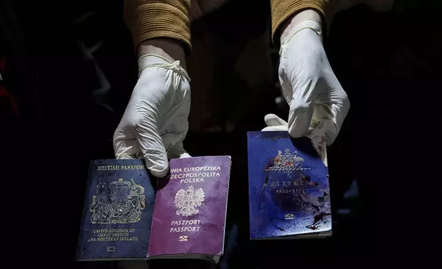 A man displays blood-stained British, Polish, and Australian passports after an Israeli airstrike, in Deir al-Balah, Gaza Strip, Monday, April 1, 2024. Gaza medical officials say an apparent Israeli airstrike killed four international aid workers with the World Central Kitchen charity and their Palestinian driver after they helped deliver food and other supplies to northern Gaza that had arrived hours earlier by ship. (AP Photo/Abdel Kareem Hana)
