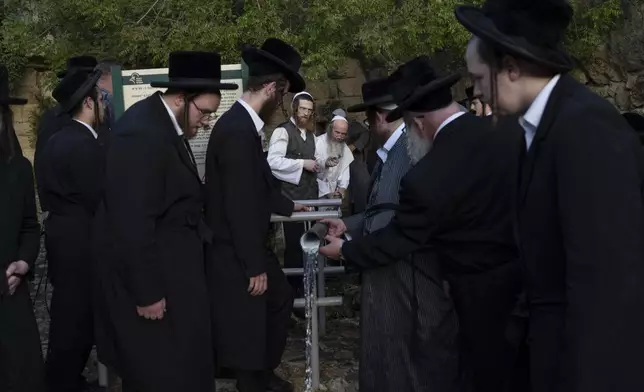 Ultra-Orthodox Jewish men gather to collect water from a spring to make matzoh, a traditional handmade unleavened bread for the holiday of Passover, during the Maim Shelanu ceremony at a mountain spring in the outskirts of Jerusalem, Sunday, April 21, 2024. (AP Photo/Leo Correa)