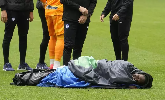Inter Milan's Marcus Thuram celebrates lying wrapped in a plastic sheet at the end of a Serie A soccer match between Inter Milan and Torino at the San Siro stadium in Milan, Italy, Sunday, April 28, 2024. Inter Milan had already clinched the Italian Serie A league title the week before. (AP Photo/Luca Bruno)
