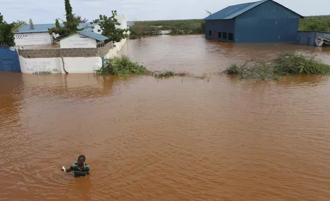 A man swims from a submerged church compound, after the River Tana broke its banks following heavy rains at Mororo, border of Tana River and Garissa counties, North Eastern Kenya, Sunday, April. 28, 2024. Heavy rains pounding different parts of Kenya have led to dozens of deaths and the displacement of tens of thousands of people, according to the U.N. (AP Photo/Andrew Kasuku)
