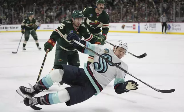 Minnesota Wild right wing Mats Zuccarello (36) trips Seattle Kraken center Yanni Gourde, front, during the second period of an NHL hockey game Thursday, April 18, 2024, in St. Paul, Minn. Zuccarello was penalized for tripping. (AP Photo/Abbie Parr)