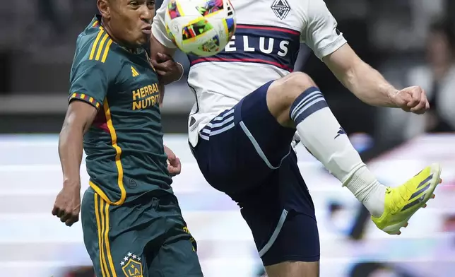 LA Galaxy's Mauricio Cuevas, left, and Vancouver Whitecaps' Brian White vie for the ball during the second half of an MLS soccer match Saturday, April 13, 2024, in Vancouver, British Columbia. (Darryl Dyck/The Canadian Press via AP)