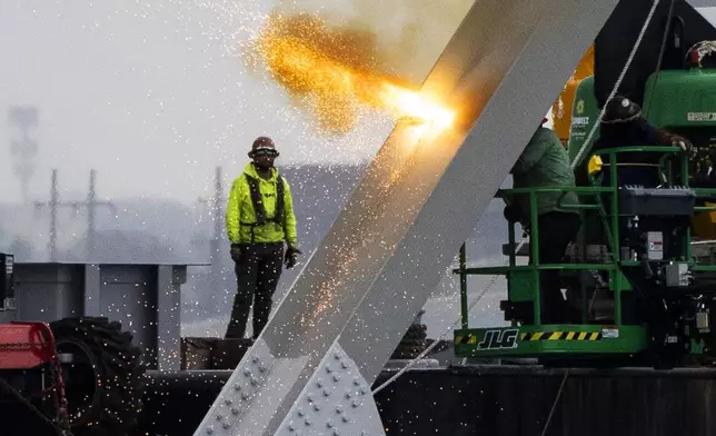 Workers are seen in the beginning stages of dismantling the steel from the frame of the collapsed Francis Scott Key Bridge, using an exothermic cutting torch, April 4, 2024, in Baltimore. (Kaitlin Newman/The Baltimore Banner via AP)