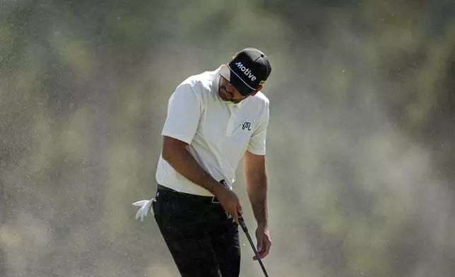 Jason Day, of Australia, shields himself from blowing sand on the 18th hole during second round at the Masters golf tournament at Augusta National Golf Club Friday, April 12, 2024, in Augusta, Ga. (AP Photo/Ashley Landis)