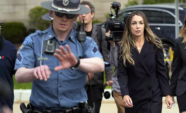 Karen Read, right, is flanked by Massachusetts State Police while leaving Norfolk Superior Court after the opening day of her trial, Monday, April 29, 2024, in Dedham, Mass. Read is charged with killing her Boston police officer boyfriend by intentionally driving her SUV into him. (AP Photo/Charles Krupa)