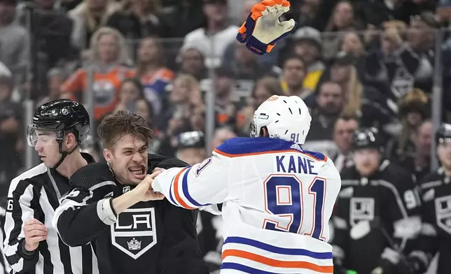 Los Angeles Kings defenseman Andreas Englund, center, and Edmonton Oilers left wing Evander Kane, right, fight during the third period in Game 3 of an NHL hockey Stanley Cup first-round playoff series Friday, April 26, 2024, in Los Angeles. (AP Photo/Mark J. Terrill)