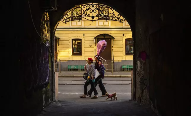Two women walk along a street in downtown Kyiv, Ukraine, Sunday, April 28, 2024. (AP Photo/Francisco Seco)