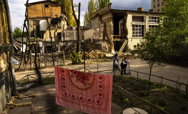 Local residents walk past debris at the Boychuk art academy that was heavily damaged during a Russian bombing at the end of March, in Kyiv, Ukraine, Tuesday, April 23, 2024. (AP Photo/Francisco Seco)