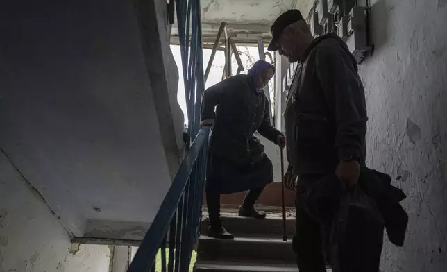 A volunteer helps Olga, 79, walk down the stairs from her apartment which was heavily damaged by a Russian airstrike, during her evacuation in Lukiantsi, Kharkiv region, Ukraine, on Tuesday, April 16, 2024. (AP Photo/Evgeniy Maloletka)