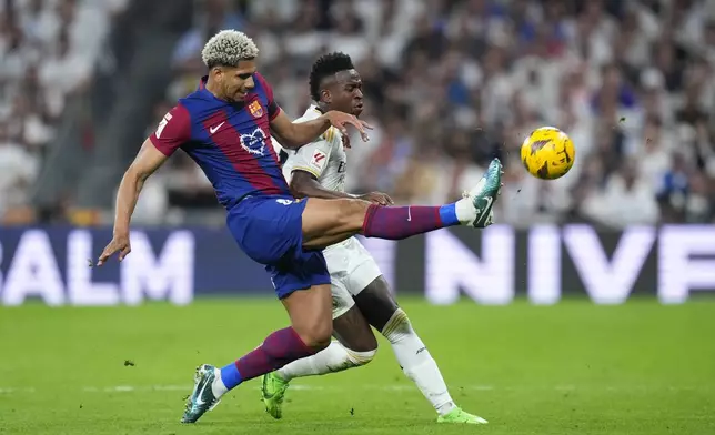 Barcelona's Ronald Araujo, left, fights for the ball with Real Madrid's Vinicius Junior during the Spanish La Liga soccer match between Real Madrid and Barcelona at the Santiago Bernabeu stadium in Madrid, Spain, Sunday, April 21, 2024. (AP Photo/Manu Fernandez)