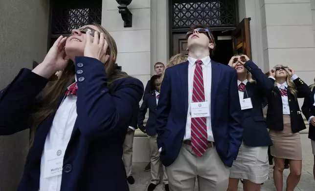 Pages for the Mississippi State Legislature take a break to view the solar eclipse on the south steps of the Mississippi State Capitol in Jackson, Monday, April 8, 2024. Legislators, staff and the pages shared the filtered eclipse glasses to see the partial eclipse that peered through afternoon clouds. (AP Photo/Rogelio V. Solis)