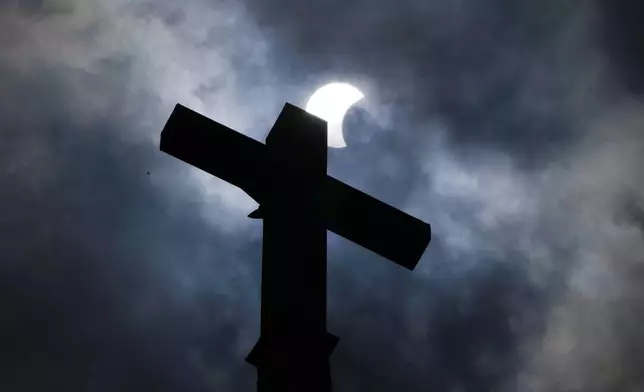 Clouds part as a partial eclipse of the sun and moon cross atop the New Sweden Evangelical Lutheran Church steeple Monday, April 8, 2024, in Manor, Texas. (AP Photo/Charles Rex Arbogast)