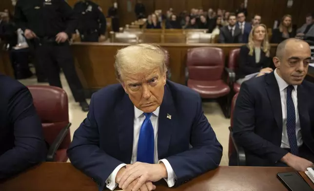 Former president Donald Trump, center, awaits the start of proceedings at Manhattan criminal court, Monday, April 22, 2024, in New York. Opening statements in Donald Trump's historic hush money trial are set to begin. Trump is accused of falsifying internal business records as part of an alleged scheme to bury stories he thought might hurt his presidential campaign in 2016. (AP Photo/Yuki Iwamura, Pool)