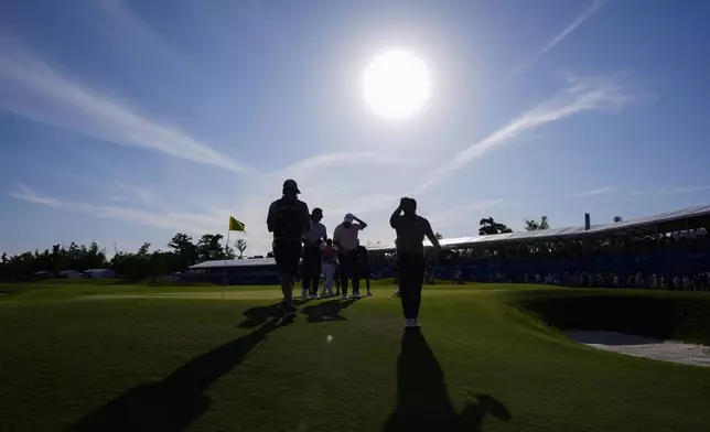 Kurt Kitayama, foreground, and Shane Lowry, of Ireland, behind, wipe their heads after finishing their day on the 18th hole during the first round of the PGA Zurich Classic golf tournament at TPC Louisiana in Avondale, La., Thursday, April 25, 2024. (AP Photo/Gerald Herbert)