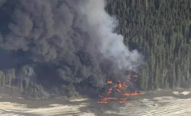 A fire burns after a Douglas C-54 Skymaster plane crashed into the Tanana River outside Fairbanks, Alaska, Tuesday, April 23, 2024. (Michaela Matherne via AP)