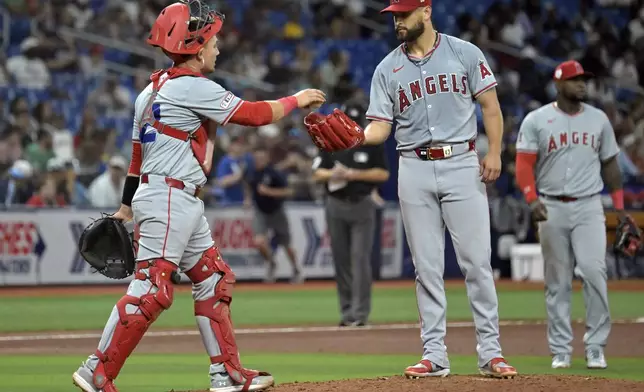 Los Angeles Angels catcher Matt Thaiss, left, walks to the mound to talk with starter Patrick Sandoval, center, during the fifth inning of a baseball game against the Tampa Bay Rays Monday, April 15, 2024, in St. Petersburg, Fla. (AP Photo/Steve Nesius)