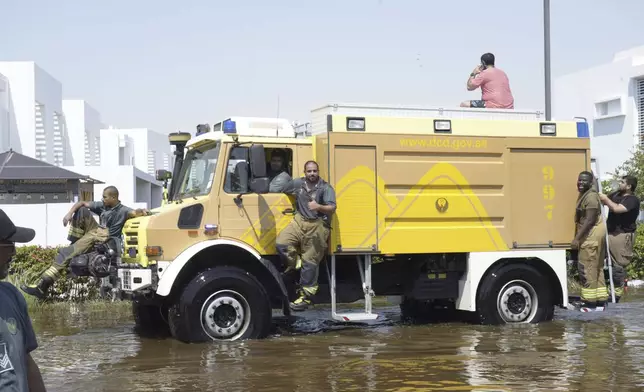 Dubai civil defense officials drive through floodwater in the Mudon neighborhood in Dubai, United Arab Emirates, Thursday, April 18, 2024. The United Arab Emirates attempted to dry out Thursday from the heaviest rain the desert nation has ever recorded — a deluge that flooded out Dubai International Airport and disrupted flights through the world's busiest airfield for international travel. (AP Photo/Jon Gambrell)