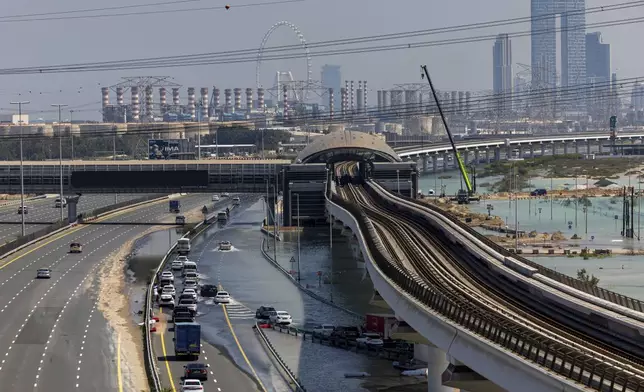 Vehicles drive through standing floodwater caused by heavy rain on Sheikh Zayed Road highway in Dubai, United Arab Emirates, Thursday, April 18, 2024. The United Arab Emirates attempted to dry out Thursday from the heaviest rain the desert nation has ever recorded, a deluge that flooded out Dubai International Airport and disrupted flights through the world's busiest airfield for international travel. (AP Photo/Christopher Pike)