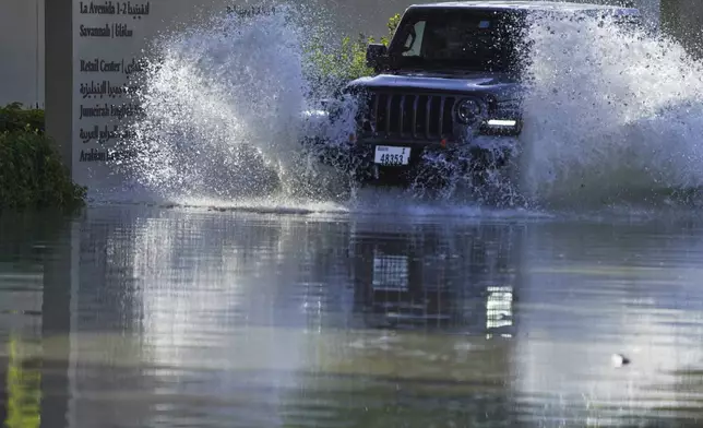 An SUV drives through floodwater covering a road in Dubai, United Arab Emirates, Wednesday, April 17, 2024. Heavy thunderstorms lashed the United Arab Emirates on Tuesday, dumping over a year and a half's worth of rain on the desert city-state of Dubai in the span of hours as it flooded out portions of major highways and its international airport. (AP Photo/Jon Gambrell)