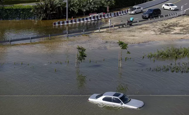 An abandoned vehicle stands in floodwater caused by heavy rain in Dubai, United Arab Emirates, Thursday, April 18, 2024. The United Arab Emirates attempted to dry out Thursday from the heaviest rain the desert nation has ever recorded, a deluge that flooded out Dubai International Airport and disrupted flights through the world's busiest airfield for international travel. (AP Photo/Christopher Pike)