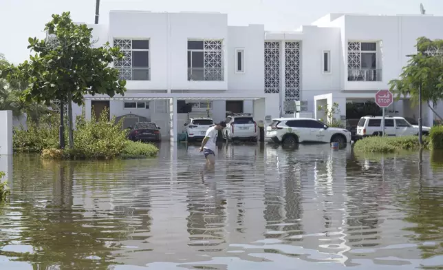 A man walks through floodwater in the Mudon neighborhood in Dubai, United Arab Emirates, Thursday, April 18, 2024. The United Arab Emirates attempted to dry out Thursday from the heaviest rain the desert nation has ever recorded — a deluge that flooded out Dubai International Airport and disrupted flights through the world's busiest airfield for international travel. (AP Photo/Jon Gambrell)