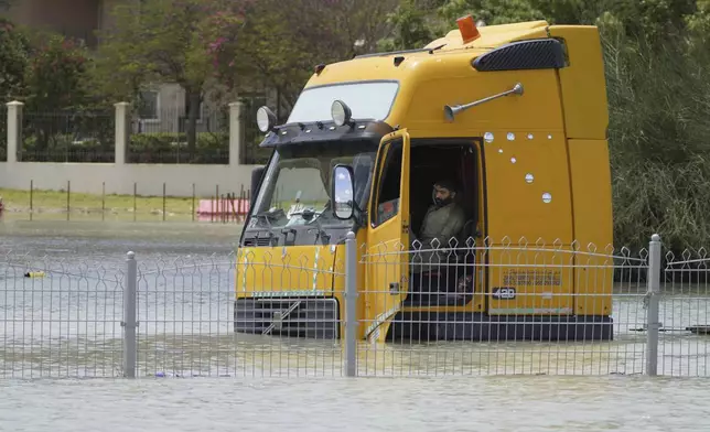 A man sits in a semitruck stuck in floodwater in Dubai, United Arab Emirates, Wednesday, April 17, 2024. The desert nation of the United Arab Emirates attempted to dry out Wednesday from the heaviest rain ever recorded there after a deluge flooded out Dubai International Airport, disrupting the world's busiest airfield for international travel. (AP Photo/Jon Gambrell)