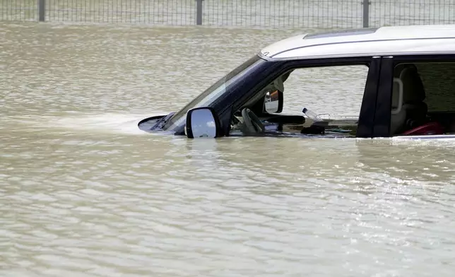 Debris floats through an SUV abandoned in floodwater in Dubai, United Arab Emirates, Wednesday, April 17, 2024. Heavy thunderstorms lashed the United Arab Emirates on Tuesday, April 16, 2024, dumping over a year and a half's worth of rain on the desert city-state of Dubai in the span of hours as it flooded out portions of major highways and its international airport. (AP Photo/Jon Gambrell)