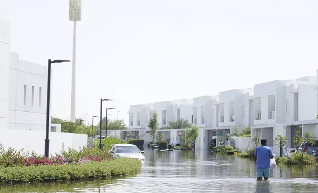 A man walks through floodwater in the Mudon neighborhood in Dubai, United Arab Emirates, Thursday, April 18, 2024. The United Arab Emirates attempted to dry out Thursday from the heaviest rain the desert nation has ever recorded — a deluge that flooded out Dubai International Airport and disrupted flights through the world's busiest airfield for international travel. (AP Photo/Jon Gambrell)