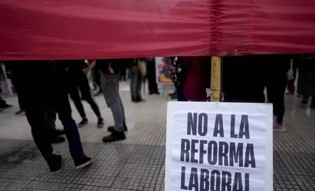 Anti-government protesters stand with a sign that reads in Spanish "No to the labor law reform" outside Congress where lawmakers debate a bill promoted by Argentine President Javier Milei that includes a broad range of economic, administrative, criminal and environmental reforms in Buenos Aires, Argentina, Tuesday, April 30, 2024. (AP Photo/Natacha Pisarenko)