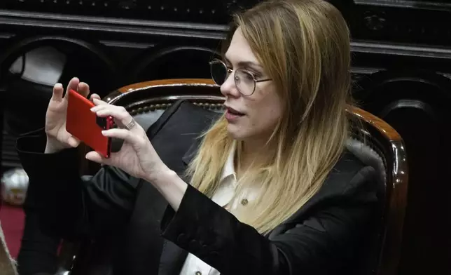 Pro-government lawmaker Lilia Lemoine holds her cell phone during the debate on a bill promoted by Argentine President Javier Milei that includes a broad range of economic, administrative, criminal, and environmental reforms, at Congress in Buenos Aires, Argentina, Tuesday, April 30, 2024. (AP Photo/Natacha Pisarenko)