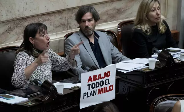 Opposition lawmaker Romina Del Plá speaks during the debate on a bill promoted by Argentine President Javier Milei that includes a broad range of economic, administrative, criminal, and environmental reforms, at Congress in Buenos Aires, Argentina, Tuesday, April 30, 2024. The sign reads in Spanish: "Down with all of Milei's plan." (AP Photo/Natacha Pisarenko)