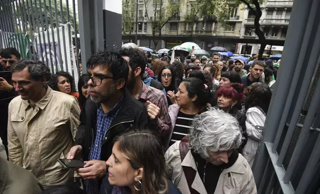 State employees enter their workplace after they were temporarily prevented from entering their workplace due to an anti-government protest in support of workers who were laid off as part of state economic downsizing measures, in Buenos Aires, Argentina, Wednesday, April 3, 2024. According to the State Workers Association, more than 11 thousand dismissals of state employees have been carried out by Javier Milei’s government. (AP Photo/Gustavo Garello)