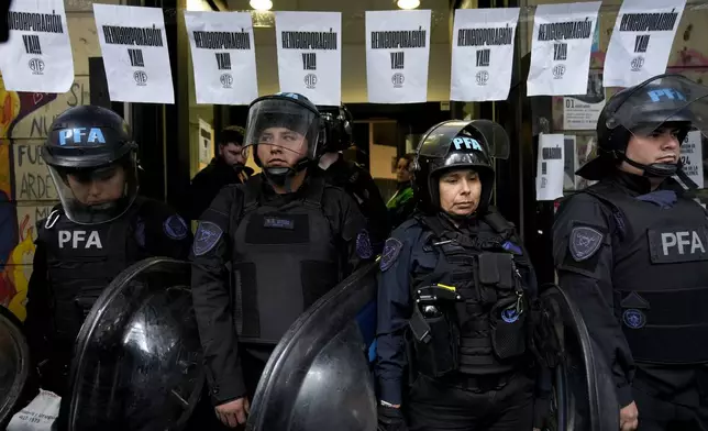 Police stand at the entrance of the National Institute against Discrimination, Xenophobia, and Racism, to prevent laid off workers from entering their workplace, in Buenos Aires, Argentina, Wednesday, April 3, 2024. According to the State Workers Association, more than 11 thousand dismissals of state employees have been carried out by Javier Milei’s government. (AP Photo/Natacha Pisarenko)