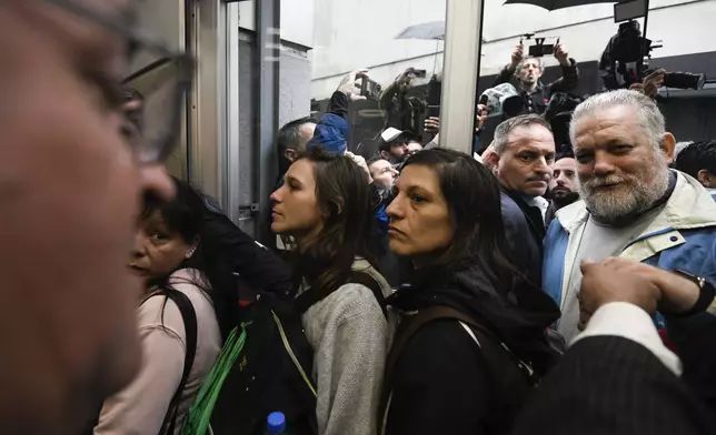 State employees enter their workplace after they were temporarily prevented from entering their workplace due to an anti-government protest in support of workers who were laid off as part of state economic downsizing measures, in Buenos Aires, Argentina, Wednesday, April 3, 2024. According to the State Workers Association, more than 11 thousand dismissals of state employees have been carried out by Javier Milei’s government. (AP Photo/Gustavo Garello)