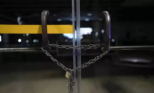A chain lock reinforces the locked door of a gas station that started closing shop at night after the killing of a worker at a nearby station a few weeks before, in Rosario, Argentina, Monday, April 8, 2024. The order to kill came from inside Ezeiza Prison from gang leaders who hired a 15-year-old hitman to kill gas station worker Bruno Bussanich on March 9. (AP Photo/Natacha Pisarenko)