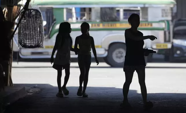 People walk under a shade during a hot day in Manila, Philippines on Monday, April 29, 2024. Millions of students in all public schools across the Philippines were ordered to stay home Monday after authorities cancelled in-person classes for two days as an emergency step due to the scorching heat and a public transport strike. (AP Photo/Aaron Favila)