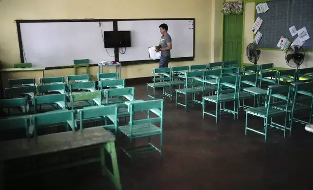 A teacher arranges papers at an empty classroom at the Justo Lukban Elementary School in Manila, Philippines on Monday, April 29, 2024. Millions of students in all public schools across the Philippines were ordered to stay home Monday after authorities cancelled in-person classes for two days as an emergency step due to the scorching heat and a public transport strike. (AP Photo/Aaron Favila)