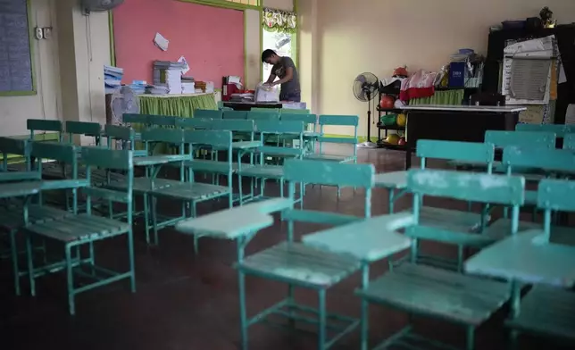A teacher arranges papers at an empty classroom as classes shifted to online mode at the Justo Lukban Elementary School in Manila, Philippines on Monday, April 29, 2024. Millions of students in all public schools across the Philippines were ordered to stay home Monday after authorities cancelled in-person classes for two days as an emergency step due to the scorching heat and a public transport strike. (AP Photo/Aaron Favila)