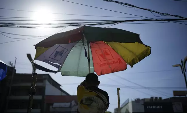 A vendor prepares his umbrella as hot days continue in Manila, Philippines on Monday, April 29, 2024. Millions of students in all public schools across the Philippines were ordered to stay home Monday after authorities cancelled in-person classes for two days as an emergency step due to the scorching heat and a public transport strike. (AP Photo/Aaron Favila)