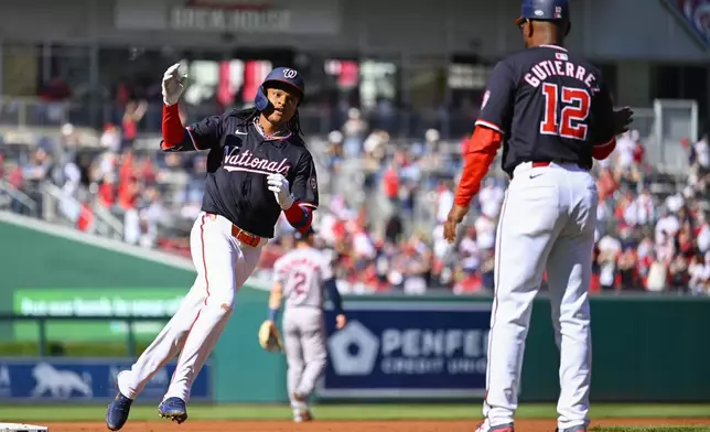 Washington Nationals shortstop CJ Abrams, left, rounds third base and is greeted by Nationals third base coach Ricky Gutierrez after hitting a solo home run during the first inning of a baseball game against the Houston Astros at Nationals Park, Saturday, April 20, 2024, in Washington. (AP Photo/John McDonnell)