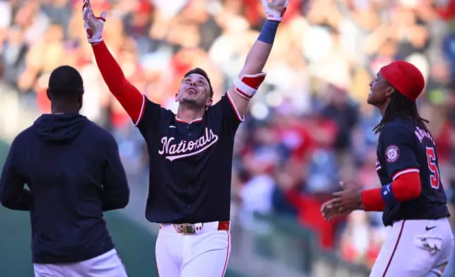 Washington Nationals' Joey Meneses, center, celebrates with teammates after driving in the game winning run in the 10th inning of a baseball game against the Houston Astros at Nationals Park, Saturday, April 20, 2024, in Washington. (AP Photo/John McDonnell)