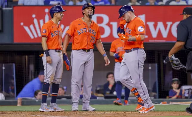 Houston Astros' Mauricio Dubón, left, José Abreu, center, wait as Victor Caratini, right, crosses home plate after Caratini's three-run home run during the fifth inning of a baseball game against the Texas Rangers, Monday, April 8, 2024, in Arlington, Texas. (AP Photo/Gareth Patterson)