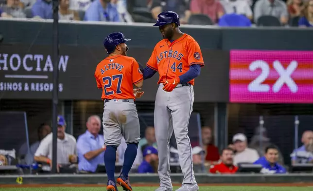 Houston Astros' Jose Altuve (27) and Yordan Alvarez (44) celebrate after scoring on a two-run single from Kyle Tucker during the fourth inning of a baseball game against the Texas Rangers, Monday, April 8, 2024, in Arlington, Texas. (AP Photo/Gareth Patterson)