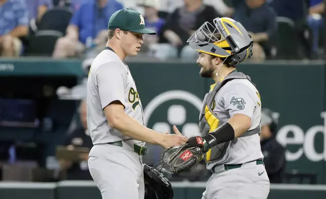 Oakland Athletics pitcher Mason Miller, left, and Oakland Athletics catcher Shea Langeliers, right, celebrate after a victory over the Texas Rangers in a baseball game Thursday, April 11, 2024, in Arlington, Texas. (AP Photo/Michael Ainsworth)