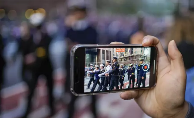 A member of the crowd films the Anzac Day parade in central the business district of Sydney, Australia, Thursday, April 25, 2024. (AP Photo/Mark Baker)