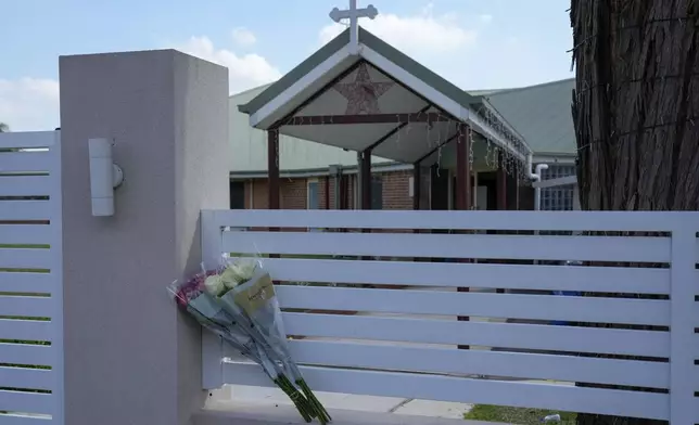 Flores sit on a fence outside the Christ the Good Shepherd church in suburban Wakely in western Sydney, Australia, Tuesday, April 16, 2024. A man has been arrested after reportedly stabbing a Christian bishop and multiple churchgoers during a televised service in Sydney Monday, April 15, 2024, police said. There were no reports of life-threatening injuries. (AP Photo/Mark Baker)