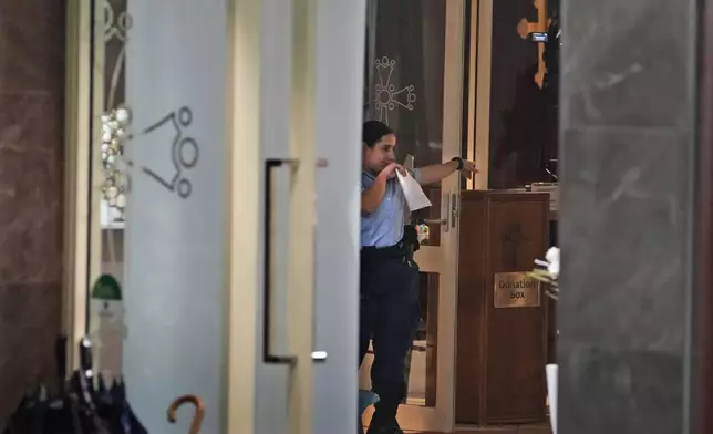A police officer investigates in a church where a bishop and churchgoers were reportedly stabbed in Sydney Australia, Monday, April 15, 2024. Police in Australia say a man has been arrested after a bishop and churchgoers were stabbed in the church. There are no life-threatening injuries. (AP Photo/Mark Baker)